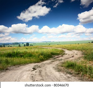 Rural dusty countryside road trough a fields with wild herbs and flowers