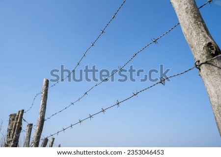 Rural fence with barbed wire on a nice day with blue sky in landscape 