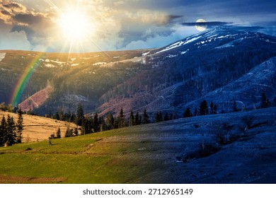 rural fields on the hill on spring equinox. day and night time change concept. snow capped mountain in the distance with sun and moon. beautiful landscape with clouds. duality and transition template