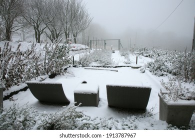 The Rural Garden In Winter Clothes. Garden Furniture Covered With Snow In Cloudy Winter Day.