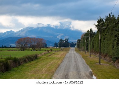 A Rural Gravel Road In Canterbury, New Zealand, With Clouds Clearing After A Recent Rain