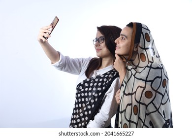 Rural Indian Bald Happy Widow With A Young Girl In Saree Taking Selfie In A Village. She Is Holding A Mobile Phone For Digitalization Concept In Rural India In White Background.