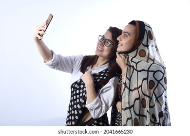 Rural Indian Bald Happy Widow With A Young Girl In Saree Taking Selfie In A Village. She Is Holding A Mobile Phone For Digitalization Concept In Rural India In White Background.