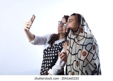 Rural Indian Bald Happy Widow With A Young Girl In Saree Taking Selfie In A Village. She Is Holding A Mobile Phone For Digitalization Concept In Rural India In White Background.