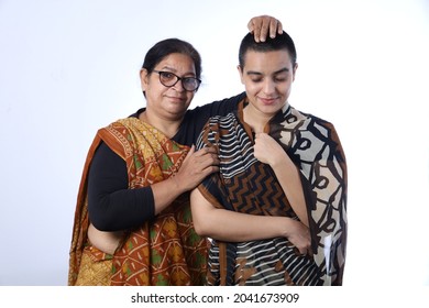 Rural Indian Bald Woman Standing Happily With Her Mother In Law, Taking Her Blessings. Both Are Wearing Saree And Portraying Happy Moment Of Togetherness In Rural Village Of India In White Background.