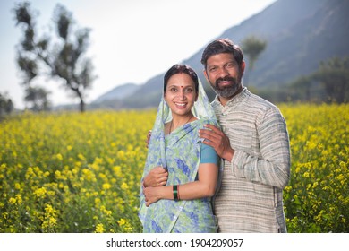 Rural Indian couple standing in rapeseed field at village