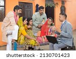 Rural indian family meeting with bank manager or financial advisor. Male agent with laptop explaining the scheme.