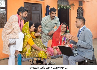 Rural Indian Family Meeting With Bank Manager Or Financial Advisor. Male Agent With Laptop Explaining The Scheme.