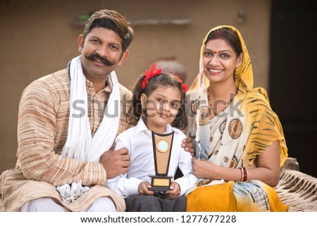 Rural Indian parents with daughter holding trophy