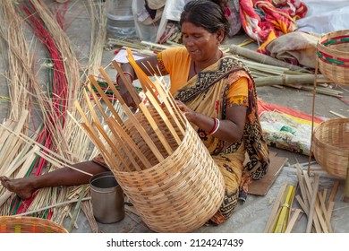 Rural Indian woman weaving a basket with bamboo straws for sale at a handicraft fair at Kolkata, India, dated January 17, 2022.