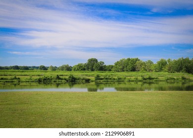 a rural lake green grass wild nature preserve park grassland pond reflection blue sky cloudscape