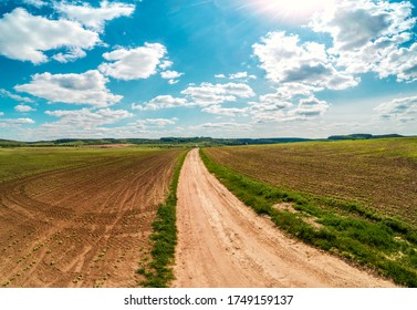 Rural landscape with beautiful sky, farmland, aerial view. View of dirt road and plowed fields in spring.