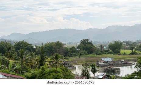 rural landscape with lush greenery, traditional houses, and misty mountains afar. - Powered by Shutterstock