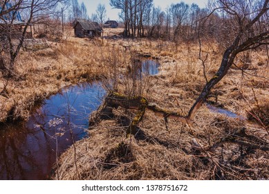 Rural Landscape With A Small River And Abandoned Rural Buildings In Backlit