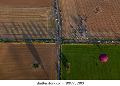 Rural Road Crossing Seen From A Hot Air Ballon. People And Another Hot Air Ballon On The Ground.