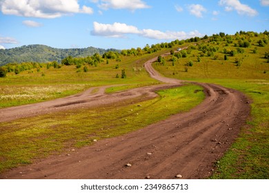 Rural road goes up to the mountain on a sunny summer day. Altai Territory, Altai District, Russia
