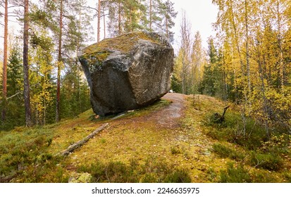 Rural road through the evergreen pine forest. Mighty stone (Korpijärven Siirtolohkare), local landmark. Atmospheric autumn landscape. Finland. Nature, ecology, ecotourism themes - Shutterstock ID 2246635975