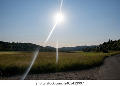 Rural scene with fields, forest, some houses, road and bright sun