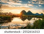 Rural scene of sunset over mountain with villager pushing bicycle on wooden bridge over the river in countryside at Bac Son Valley, Lang Son, Vietnam