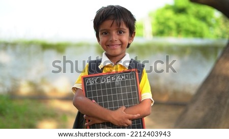 Rural School boy holding slate with English alphabet. Indian child writing A B C D alphabet on Chalkboard