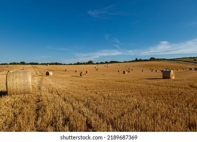 A Rural South Downs Summer Landscape, With Hay Bales In A Newly Harvested Field