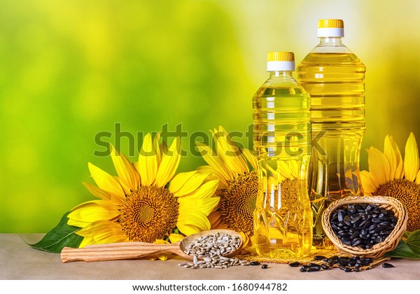 Rural still-life - sunflower\
oil in bottles with flowers of sunflower (Helianthus annuus),\
closeup