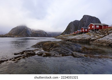 Rural view of Reine in winter, Lofoten islands, Norway. Landscape with snowy mountains, high rocks and fishermen village with traditional colored buildings.