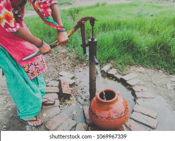 Rural Woman Taking Drinking Water From Hand Pump In A Clay Pot