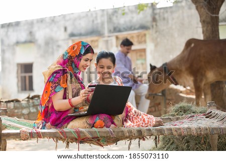 Rural woman using laptop with her daughter.