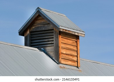 Rural Wooden Air Vent Cupola Chimney On Blue Metal Roof Against Blue Sky