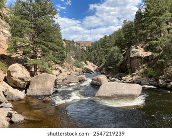 Rushing River with large rocks and trees with a blue sky and clouds  - Powered by Shutterstock