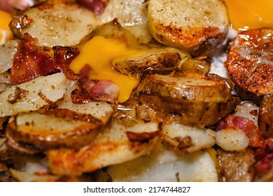 Russet Potato With Skin, Bacon And Eggs Frying On The Stove.
