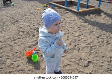 RUSSIA ABAKAN. May 1, 2021. Happy Little Child In A Gray Tracksuit And Adidas Hat Eating Ice Cream.