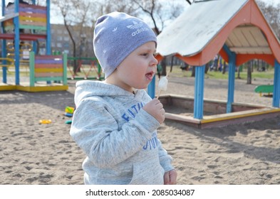 RUSSIA ABAKAN. May 1, 2021. Happy Little Child In A Gray Tracksuit And Adidas Hat Eating Ice Cream.