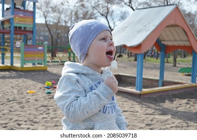 RUSSIA ABAKAN. May 1, 2021. Happy Little Child In A Gray Tracksuit And Adidas Hat Eating Ice Cream.