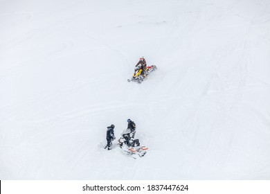 Russia, Adygea, Lago Naki, February 21, 2013: Man On BRP Snowmobile Ride Near Snowmobile  Stuck In Deep Snow On A Mountainside.