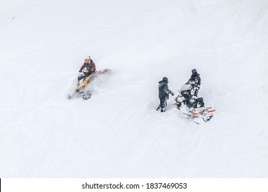 Russia, Adygea, Lago Naki, February 21, 2013: Man On BRP Snowmobile Ride Near Snowmobile  Stuck In Deep Snow On A Mountainside.