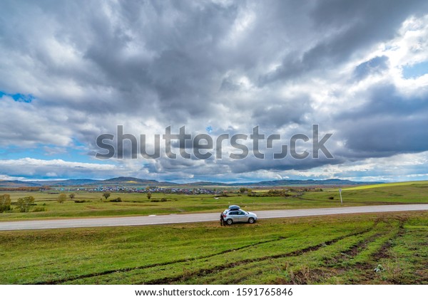 Russia, Bashkortostan Ural. Picturesque\
panorama from the road to the village and mountains on the horizon.\
Rest motorists at the edge of the\
road.