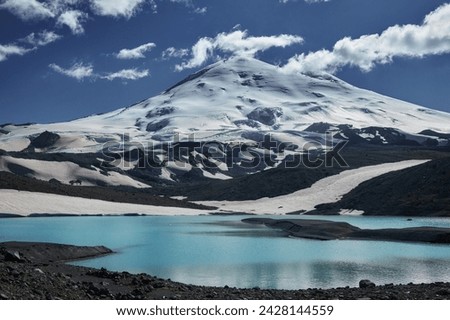 Russia Caucasus, Mount Elbrus towers majestically, adorned in pristine snow and ice. Alpine landscape boasts panoramic views of rugged ridges, serene valleys, and icy glaciers under the vast blue sky