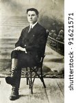 RUSSIA - CIRCA 1912: Old photo printed in Russia shows young man sitting on a chair, circa 1912