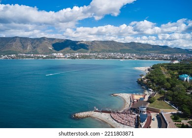 Russia, Gelendzhik, September 26, 2022: A Sea Bay With Turquoise Water Under A Blue Sky With White Clouds. A Resort Town Is Located Far Away At The Foot Of The Mountains. Aerial Photography.