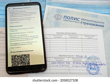 Russia, Kemerovo - 16.10.2021. Russian Compulsory Medical Insurance Policy And Certificate Of Vaccination Against COVID-19, Smartphone With An Open Website Of Public Services And QR Code