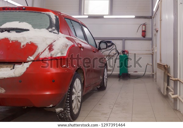 Russia Kemerovo 2019-01-05 Back of Suzuki Swift\
bright red small car in dirt snow on professional car wash. Concept\
comprehensive care for exterior, interior with vacuum cleaner, \
chemical detergent
