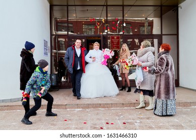 Russia, Kirov - January 24, 2019: Bride And Big Fat Groom After Wedding And Marriage Registration Near Registry Office And Guests And Relatives Meeting Them With Rose Petals In An Autumn Or Winter Day