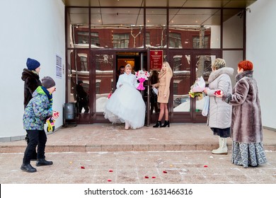 Russia, Kirov - January 24, 2019: Bride And Big Fat Groom After Wedding And Marriage Registration Near Registry Office And Guests And Relatives Meeting Them With Rose Petals In An Autumn Or Winter Day