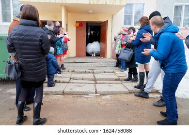 Russia, Kirov - March 22, 2019: Bride And Big Fat Groom After Wedding And Marriage Registration Near Registry Office And Guests And Relatives Meeting Them With Rose Petals In An Autumn Or Winter Day