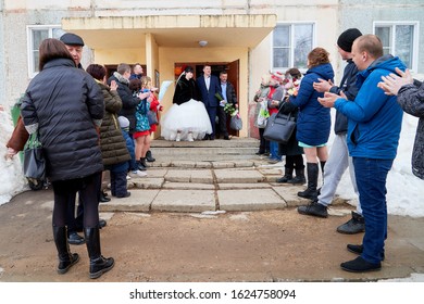 Russia, Kirov - March 22, 2019: Bride And Big Fat Groom After Wedding And Marriage Registration Near Registry Office And Guests And Relatives Meeting Them With Rose Petals In An Autumn Or Winter Day