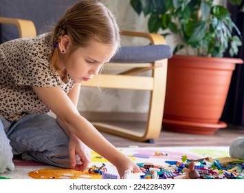 Russia, Krasnodar 12.18.2022 Build a Lego house out of bricks. Little blonde girl plays with colorful toy blocks at home, sitting on the floor in the living room. Builds and stacks. Educational games - Shutterstock ID 2242284397