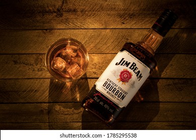 Russia, Krasnoyarsk, July 28, 2020: a bottle of Jim beam Bourbon from Kentucky and a glass of ice on a light brown wooden background.