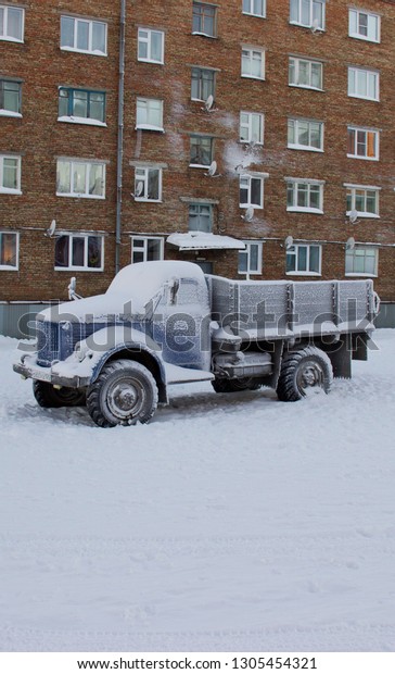 Russia, Krasnoyarsk\
region, Igarka city, winter 2016: Soviet Truck GAZ-51. Car covered\
in hoarfrost. Cold frosty weather. Funny frozen car on the street\
of the northern city.  